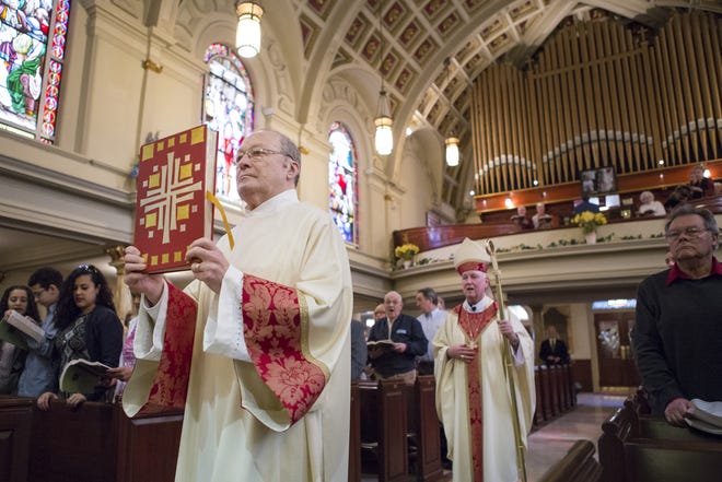 Deacon Bob Levesque carries the Bible to the altar ahead of Bishop Francis Malooly during Easter Mass at the Cathedral of St. Peter on Sunday morning in Wilmington in 2015.