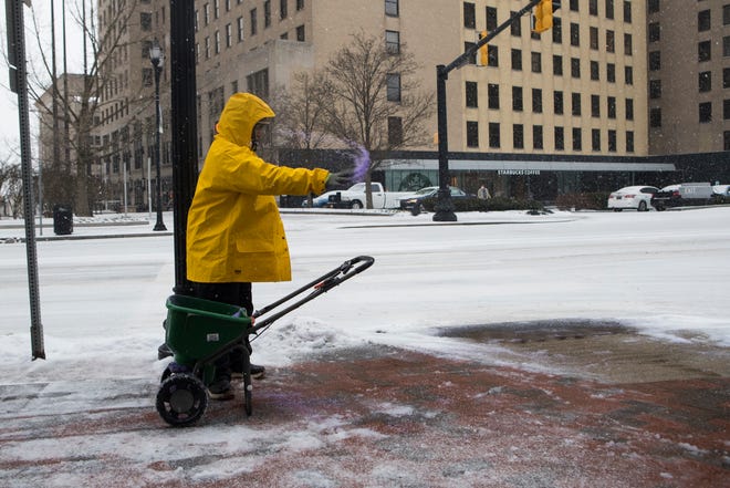 A man works to de-ice the sidewalk in downtown Wilmington Thursday, Feb. 18, 2021.