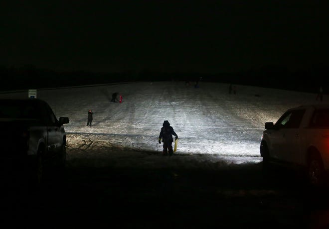 Headlights help keep the sledding going after normal closing time at Glasgow Park's sledding hill early Thursday evening, Feb. 18, 2021.